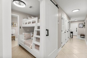 A bedroom with bunk beds, a wardrobe, and a bathroom in the background.