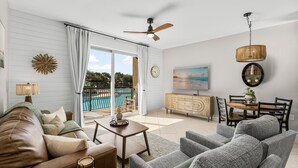 Un vaste espace de vie avec vue sur la piscine, un ventilateur de plafond et un ensemble de mobilier pour la salle à manger.