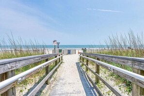 A wooden boardwalk leading to a beach with a lifeguard tower in the distance. - Bluewater Resort 513 (Myrtle Beach)