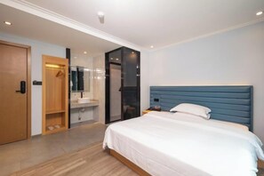 A modern hotel room with a large bed, a wooden door, a bathroom with a mirror, and a glass partition. - Qicheng Hotel (Shenzhen Guanlan Dahe Road) (Shenzhen)