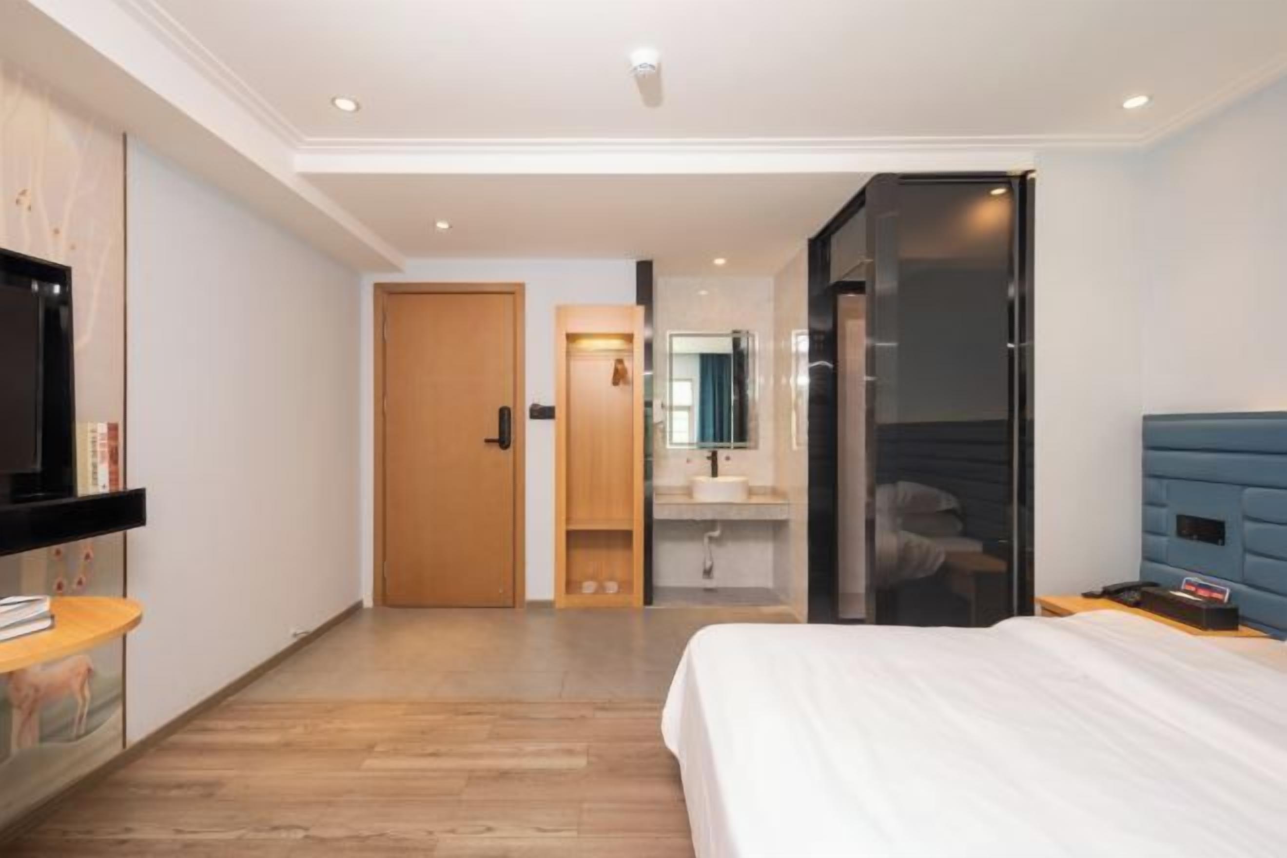 Quarto de hotel moderno com cama, televisão, banheiro e guarda-roupa.
