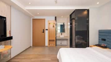 Quarto de hotel moderno com cama, televisão, banheiro e guarda-roupa.