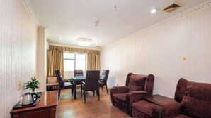 Ein Zimmer mit einem Esstisch, Stühlen, einer Couch und einem kleinen Schrank.