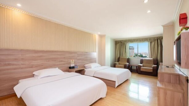 Ein Hotelzimmer mit zwei Betten, einem Schreibtisch, einem Stuhl und einem Fernseher.