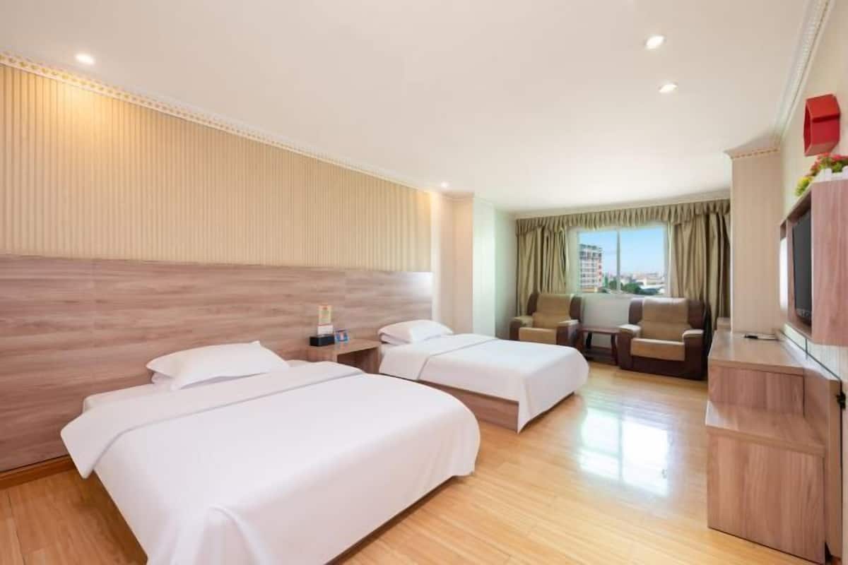 A hotel room with two beds, a desk, a chair, and a TV.