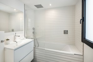 Une salle de bain moderne avec une douche à parois de verre, un meuble-lavabo blanc et un grand miroir.