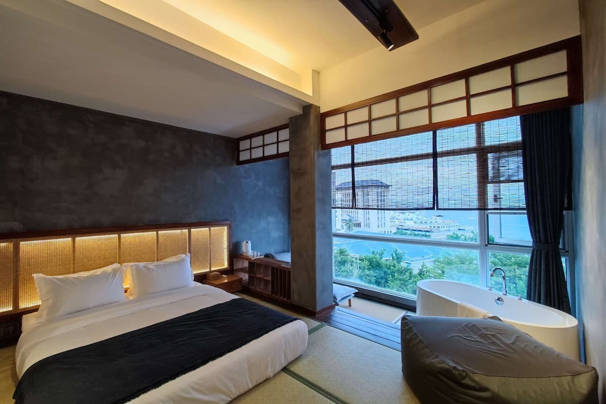 Ein modernes Hotelzimmer mit einem großen Bett, einer Sitzecke und Blick auf die Stadt.
