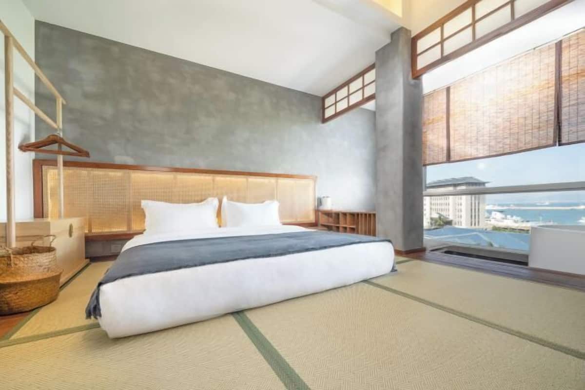 Ein modernes Hotelzimmer mit einem großen Bett, Blick auf die Stadt und einem großen Fenster.