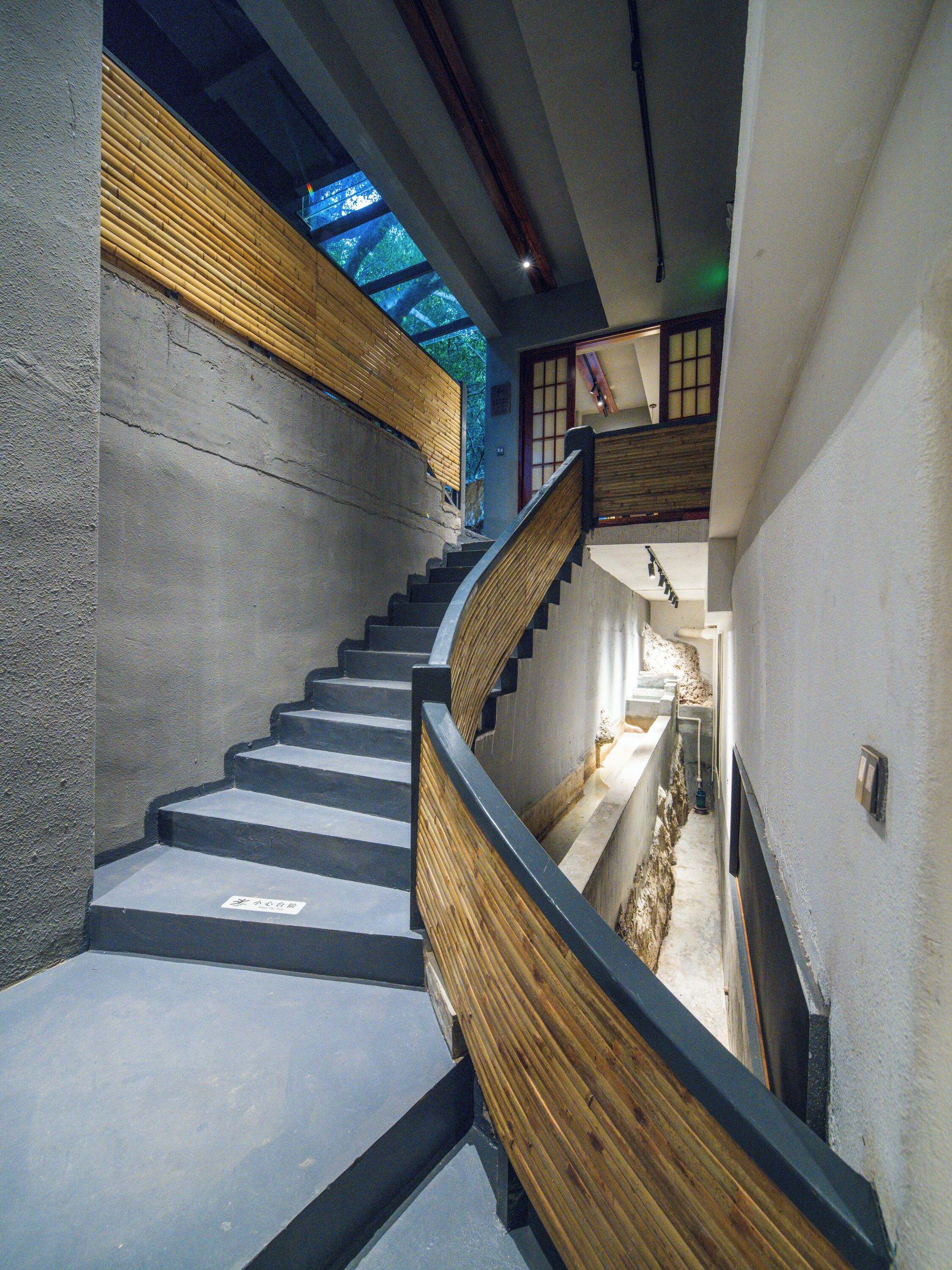 Una escalera con barandillas de madera y un muro de concreto.