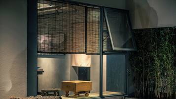 A room with a large window, a wooden stool, and a small table.