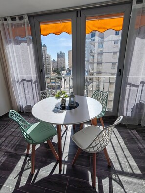 Un balcon avec une table ronde, des chaises et une petite plante.