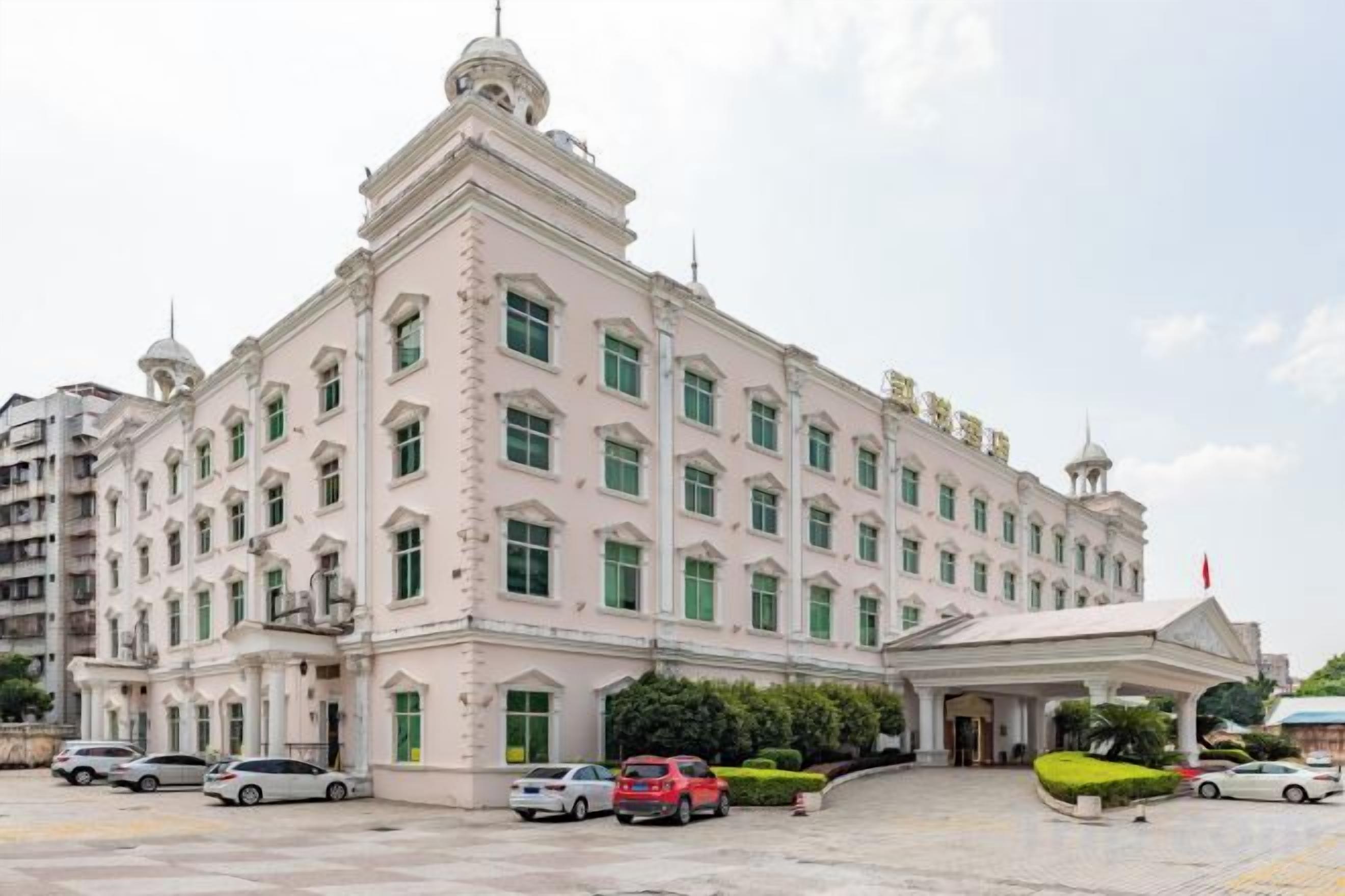 Un edificio grande de varios pisos con fachada simétrica, múltiples ventanales y una entrada destacada con toldo.