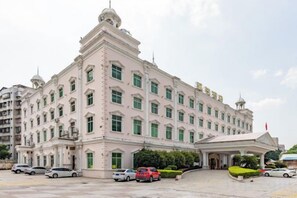 A large, multi-story building with a symmetrical facade, multiple windows, and a prominent entrance with a canopy. - Kaiyue Hotel (Shaoguan)