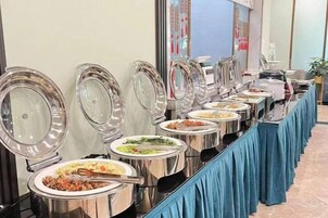 Un montaje tipo bufé con varias estaciones de comida, cada una con un recipiente cubierto.