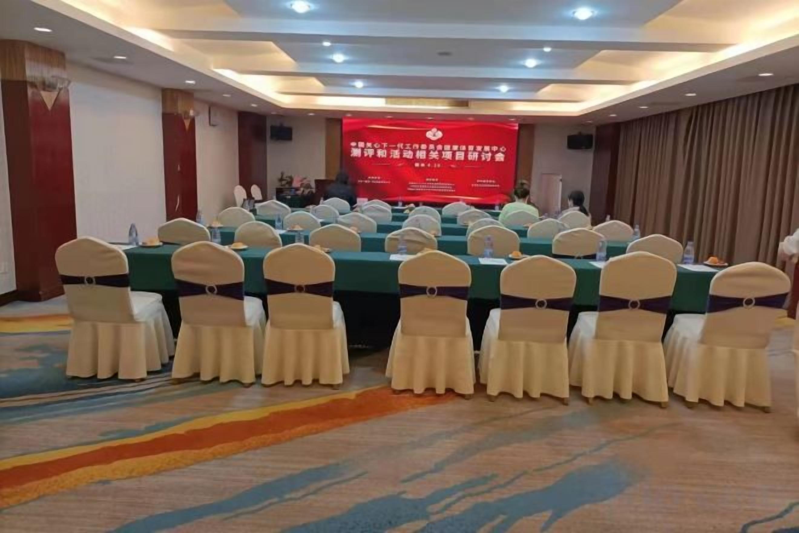 A conference room with multiple tables and chairs, a podium, and a red banner with text.