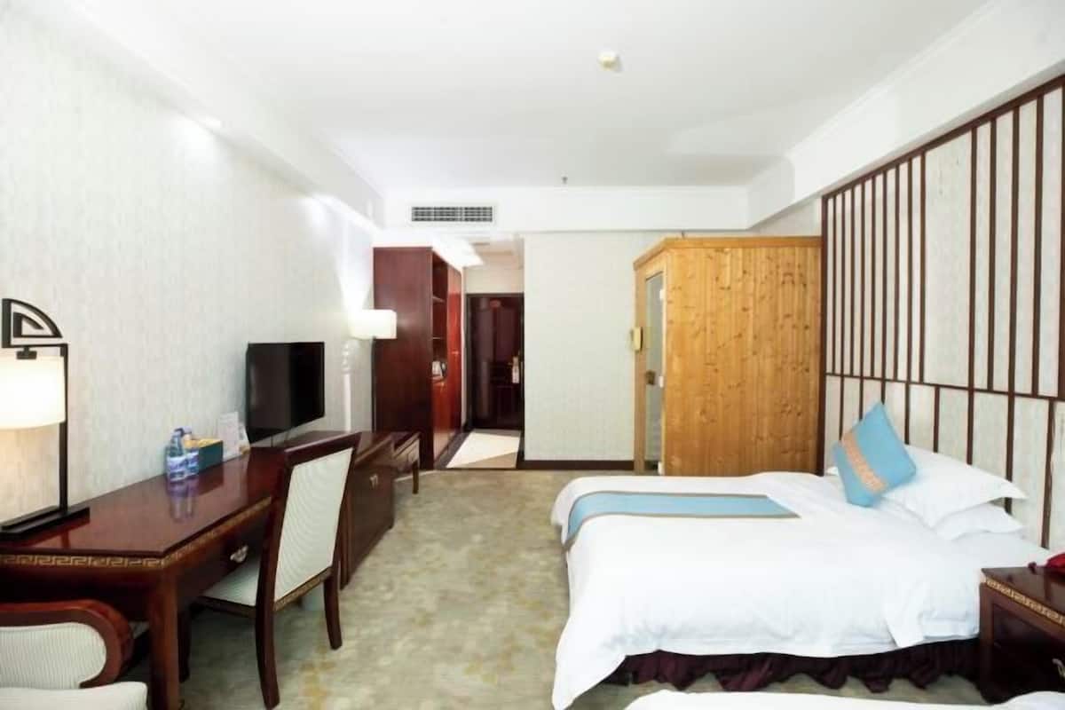 Habitación de hotel con cama, escritorio con silla, televisor y armario de madera.