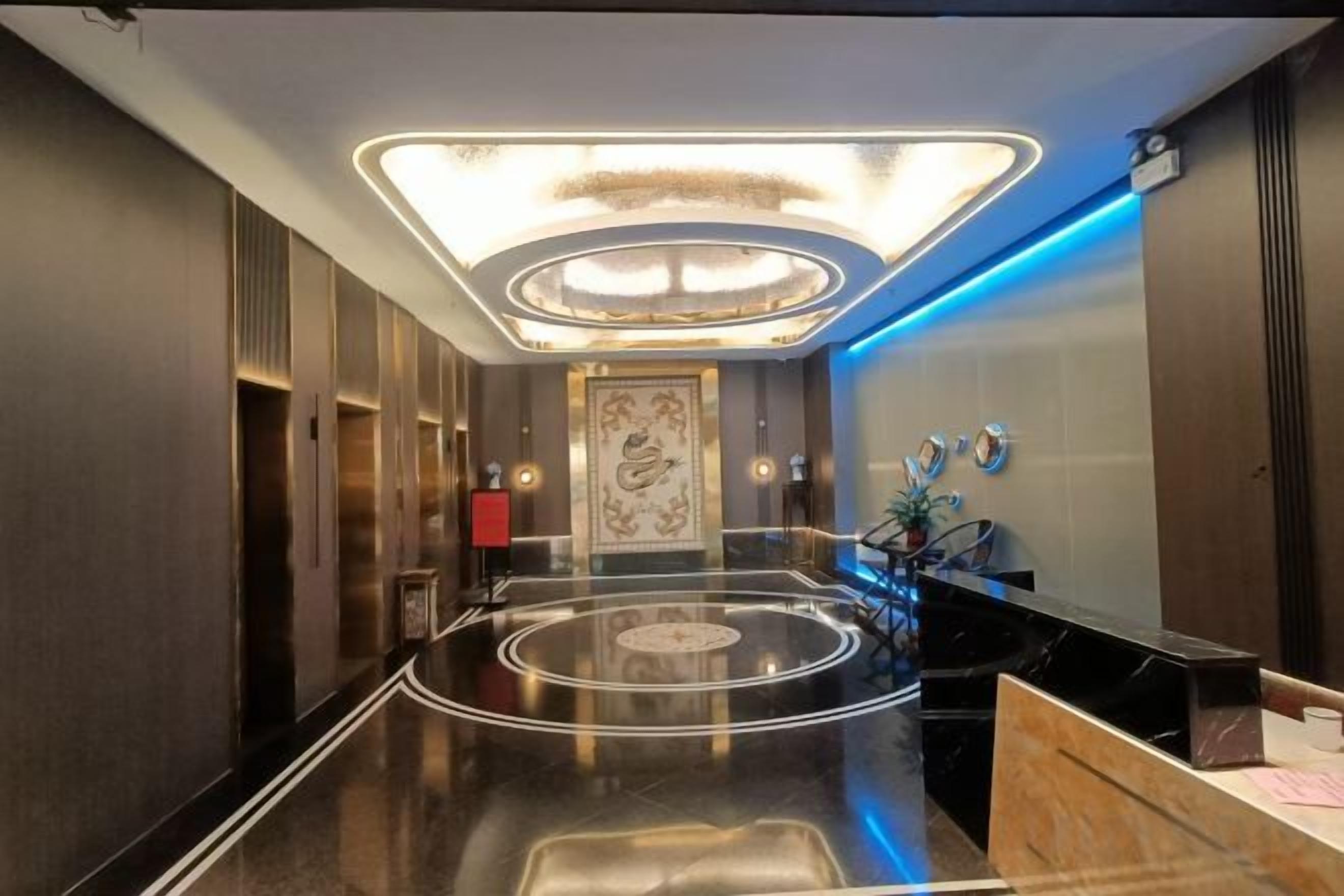 A hotel lobby with a central circular design, a reception desk, and a modern ceiling light fixture.