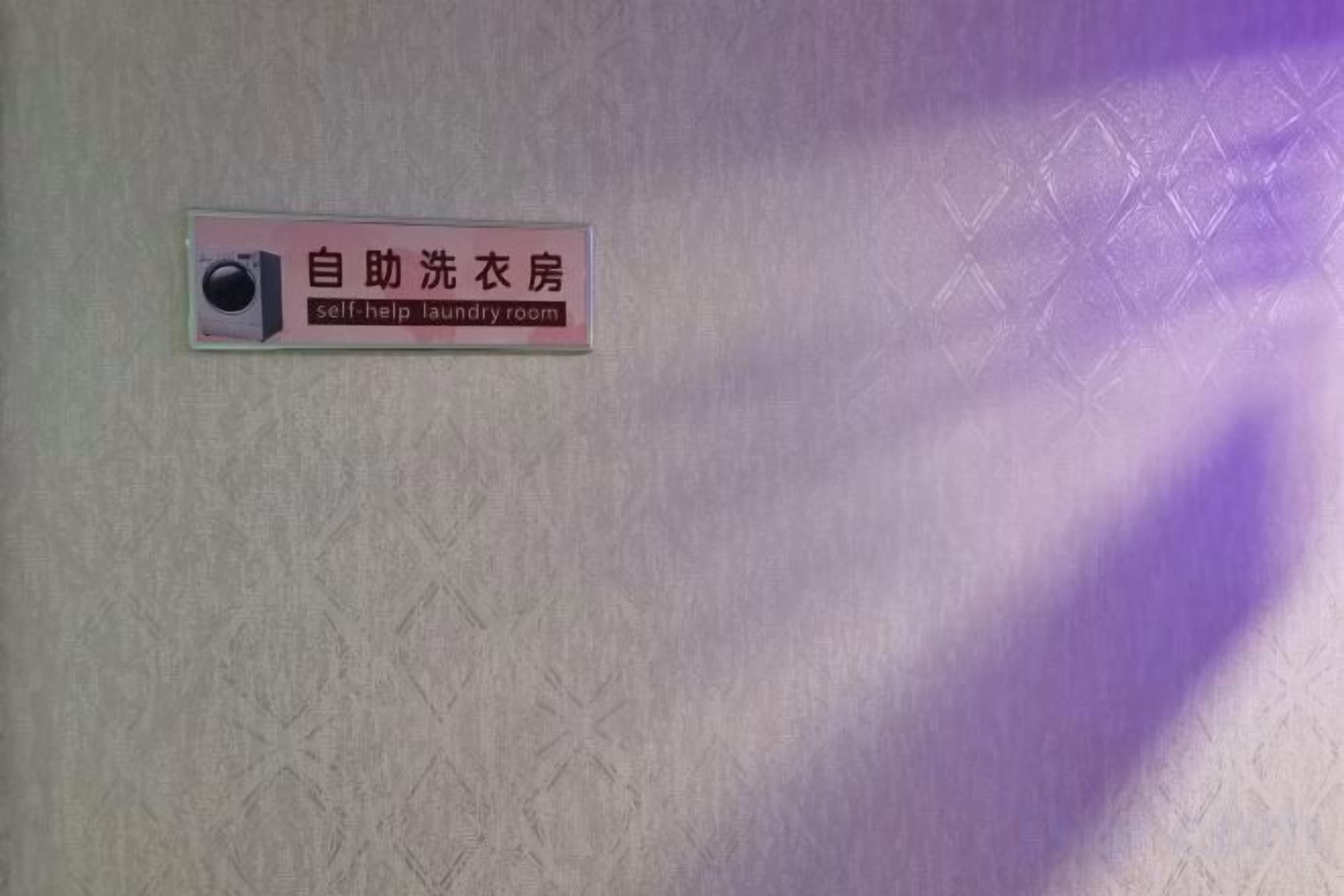 A wall with a sign indicating a self-help laundry room.