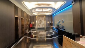 A modern hotel lobby with a polished floor, a central light fixture, and a reception desk. - Kaiyue Hotel (Shaoguan)