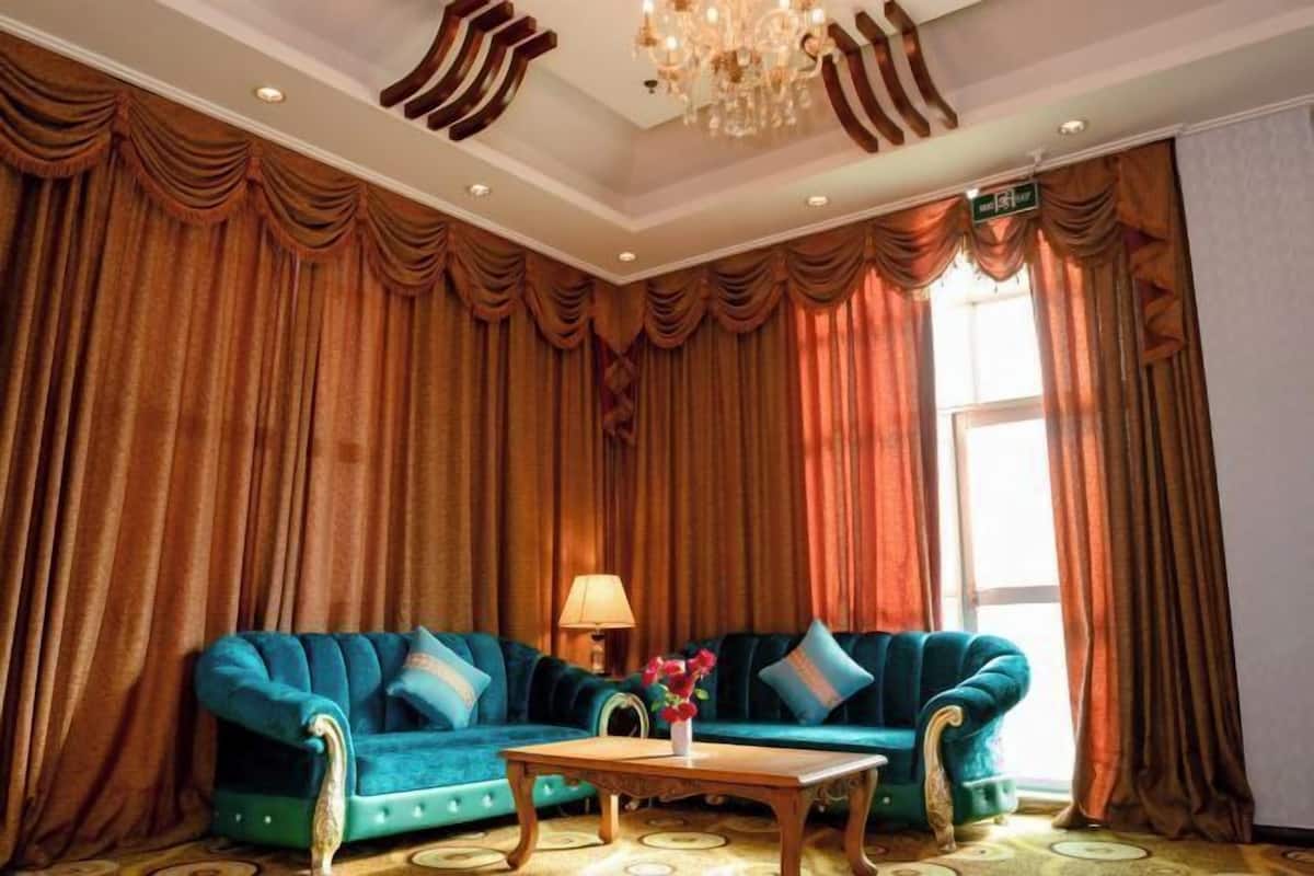 Une pièce avec un canapé de couleur turquoise, une table basse en bois et un lustre.