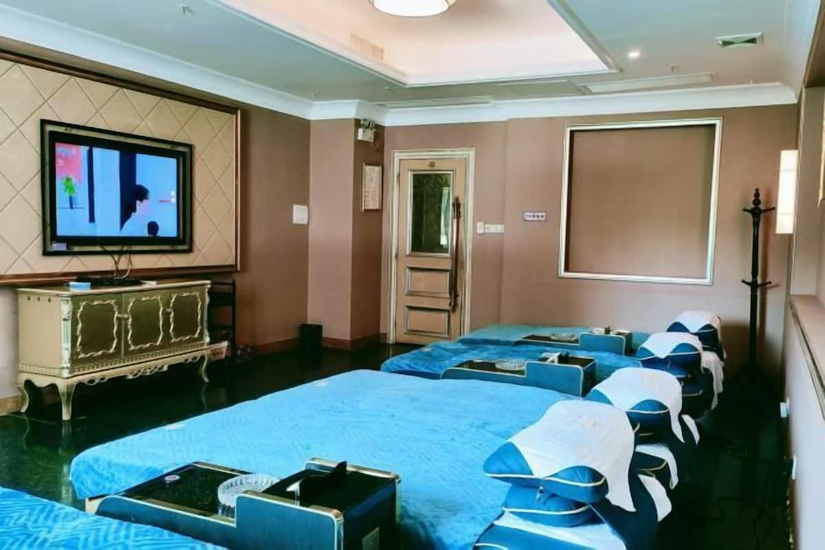 Habitación de hotel con varias camas, un televisor, un armario y una puerta.