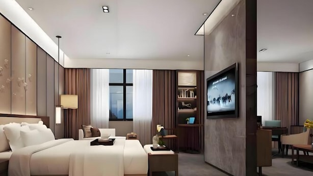 A modern hotel room with a large bed, a TV mounted on the wall, a desk, and a bookshelf. - Kaiyue Hotel (Shaoguan)