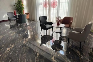 Un vestíbulo con piso de mármol, una mesa redonda y cuatro sillas.