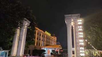 A hotel entrance with classical columns and illuminated signage.