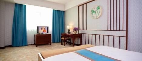 A hotel room with a bed, a desk, a television, and a decorative wall panel.