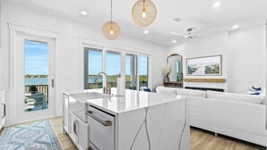 A modern kitchen with a large island, white cabinetry, and a view of the outdoors. - Luxury 10 BR Beach House Amazing View Private Pool (Gulf Shores)