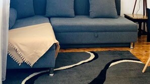 Una sala moderna con un sofá gris, una manta color beige y una lámpara de pie.
