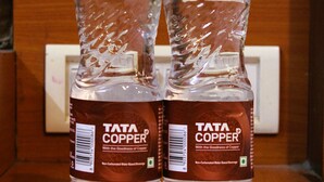 Deux bouteilles d’eau minérale non gazeuse de la marque Tata Copper, posées sur une surface en bois.