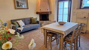 Een gezellige woonkamer met een open haard, een eettafel en een bank.