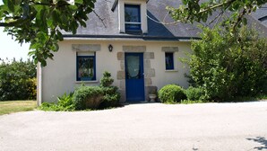 A two-story house with a blue door, a small window, and a stone wall. - Gite Camélias 700 m from the sea and the beach, 3 stars, Portsall, GR34 (Ploudalmézeau)