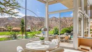 A modern outdoor dining area with a view of mountains and a pool.