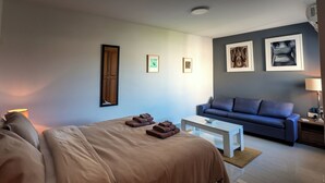 A hotel room with a bed, a sofa, a coffee table, and artwork on the walls. - Bellavista Bayview Penthouse Terrace (Marsaskala)