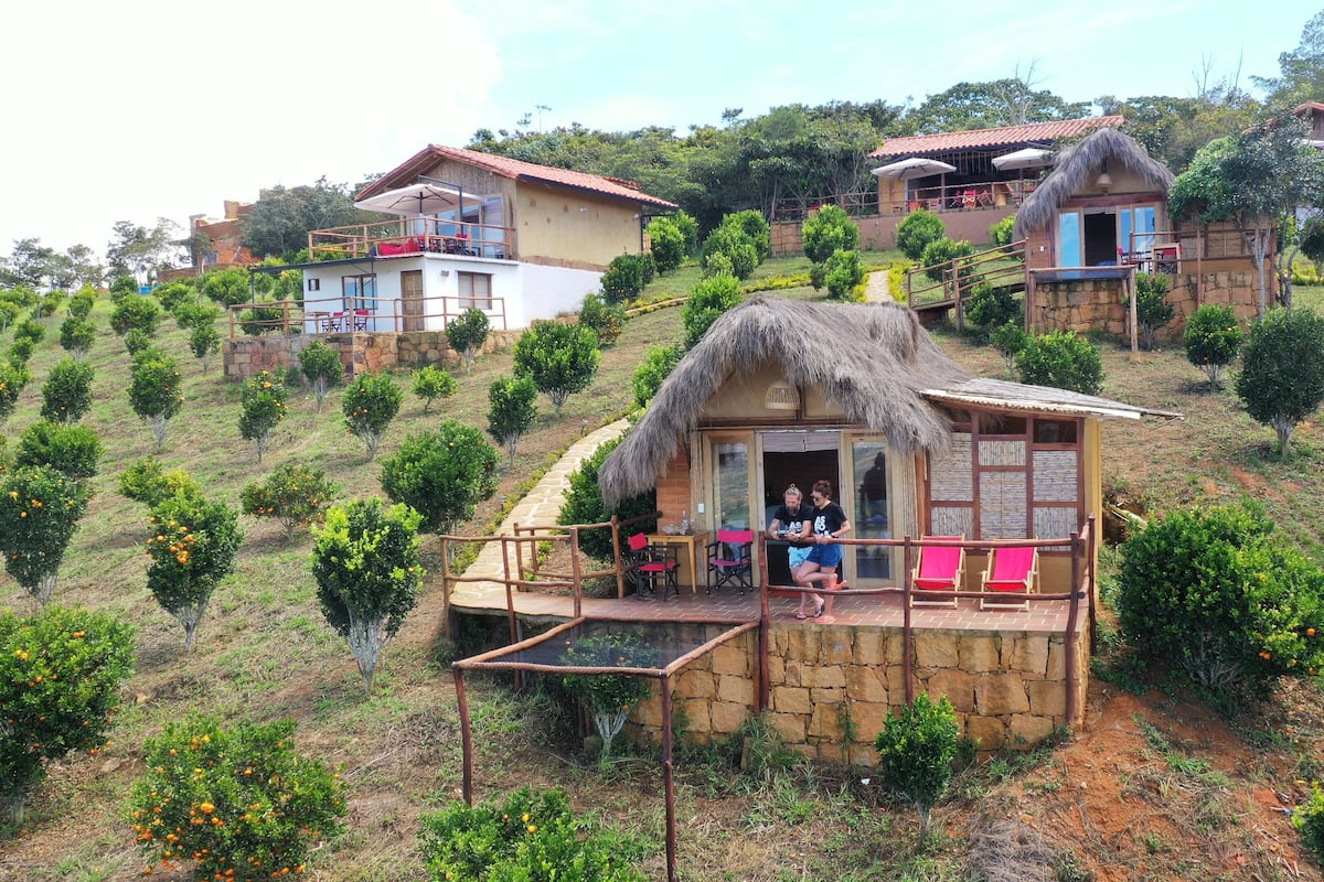 A hillside property with multiple cottages, each featuring a thatched roof and stone walls.