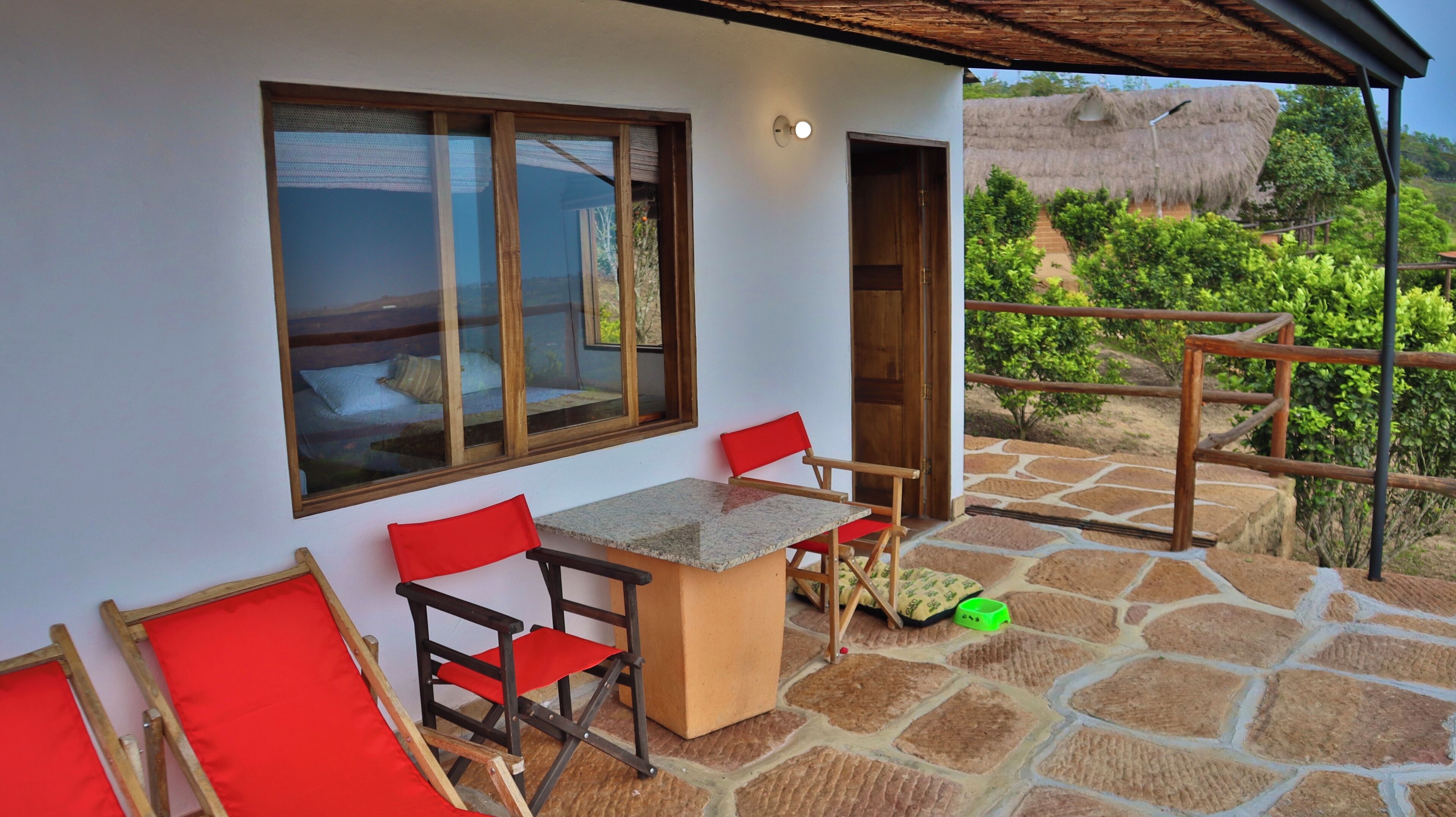 Una habitación con piso de piedra, una mesa de madera y dos sillas rojas.
