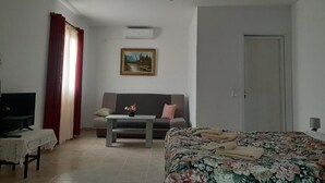 Una habitación con cama, sofá, televisión y un cuadro en la pared.