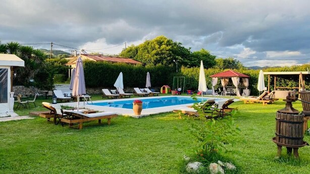 Un patio trasero con piscina, sillas de descanso y sombrillas.