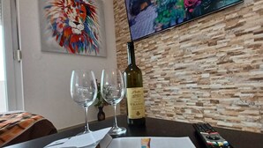 A hotel room with a wooden wall, a painting of a lion, a television, a bottle of wine, and a remote control. - Beachfront Apartment With Balcony and Sea View (Vrsi)