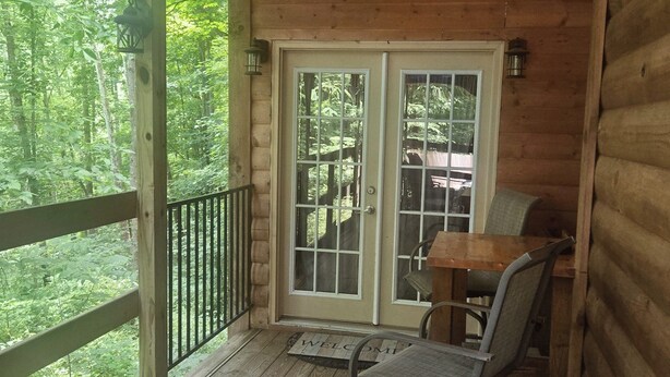 A wooden cabin with a porch, a dining table, and chairs.