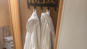 A bathroom with a towel rack holding white towels, a wooden door, and a towel dispenser.