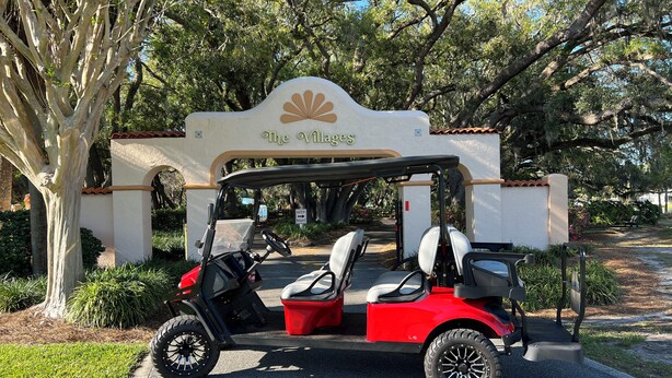 Golfiauton voi nähdä pysäköitynä rakennuksen edessä, ja rakennuksen kyltissä lukee: ”The Villages”.