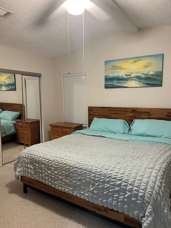 A bedroom with a bed, a nightstand, a dresser, a mirror, and a painting on the wall.