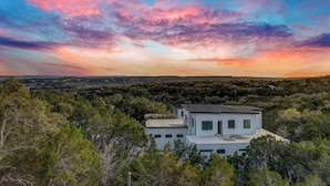 Una casa moderna con techo plano, rodeada de abundante vegetación y un paisaje pintoresco.