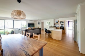 A spacious living area with a wooden dining table, a sofa, and a kitchen area with a central island.