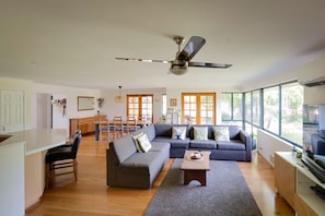 A spacious living area with a large sofa, a dining table, and a kitchen in the background.