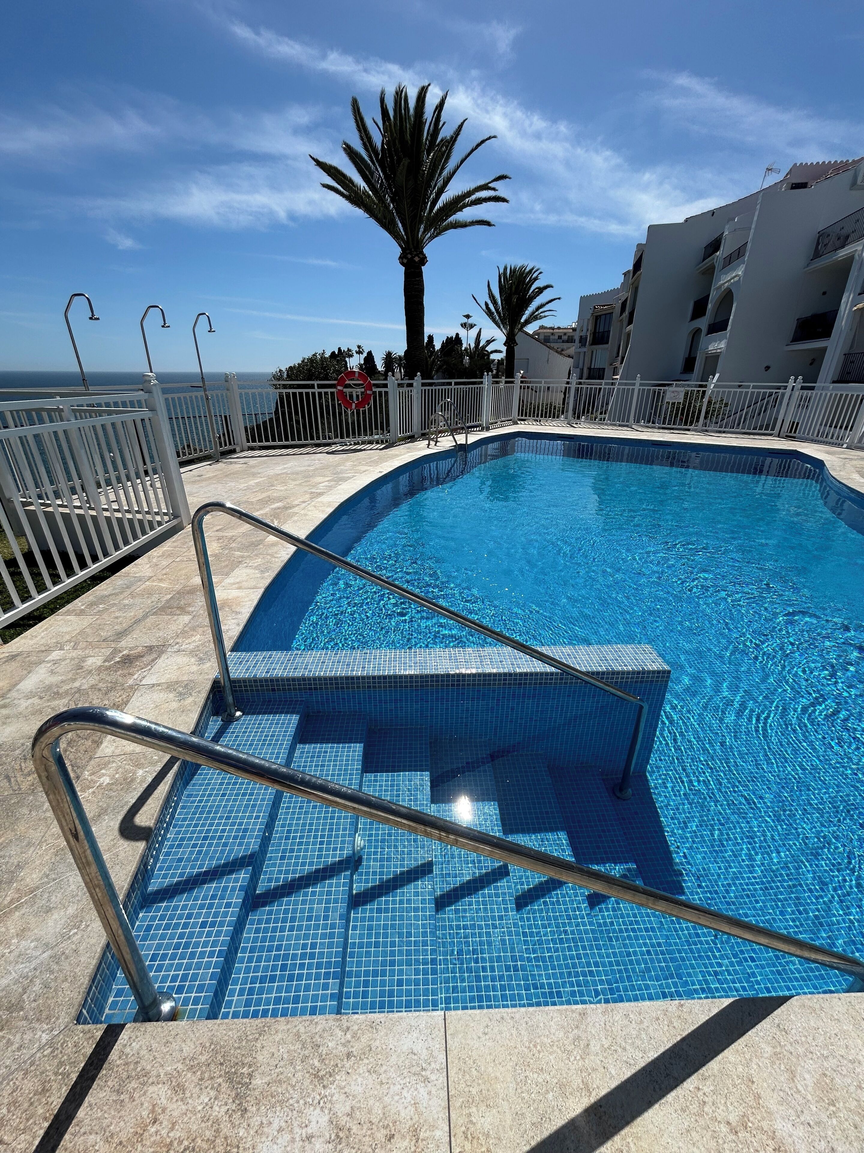 A swimming pool with tiled steps and a white metal railing.