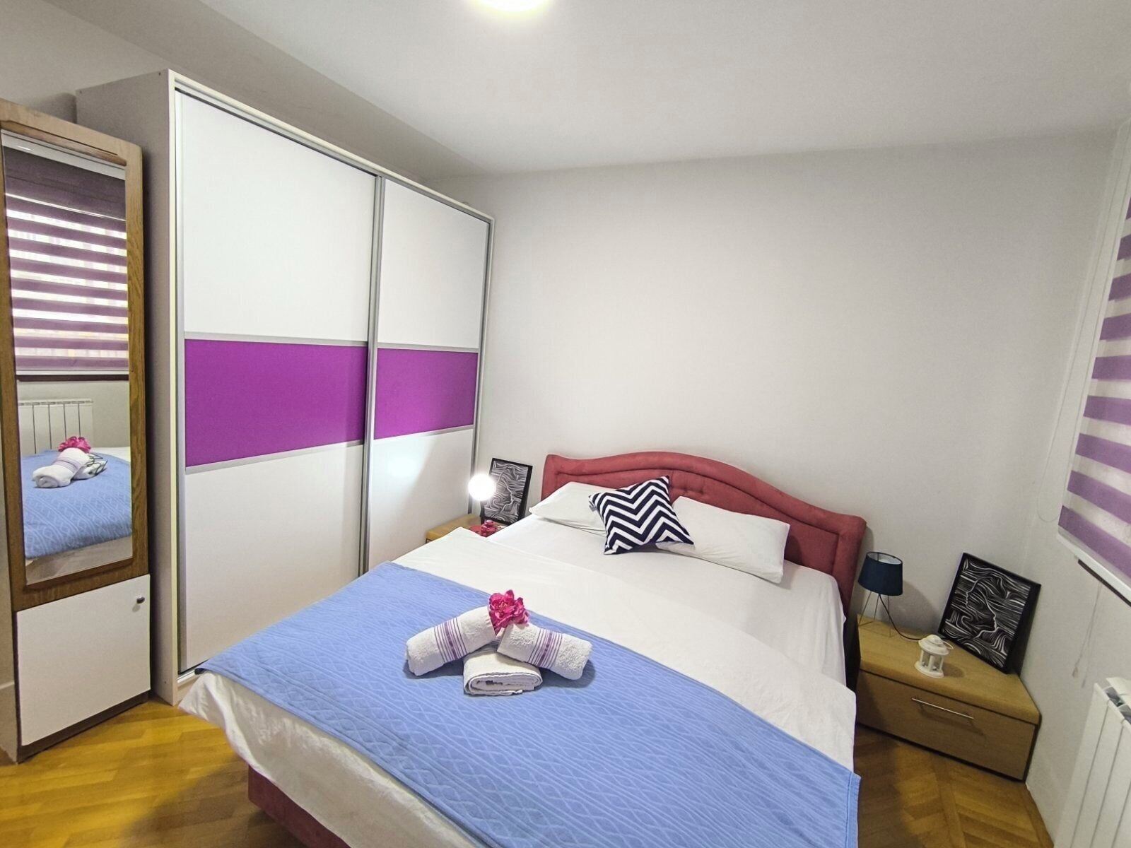 A neatly arranged bedroom with a bed, a wardrobe, a bedside table, and a nightstand.